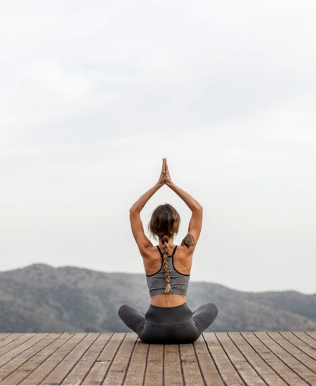 vista-posterior-mujer-haciendo-yoga-al-aire-libre